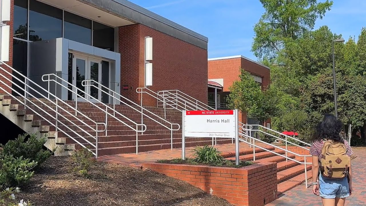 A student walks past Harris Hall on a sunny day.
